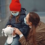 Mujer y niña en la calle con mascarillas