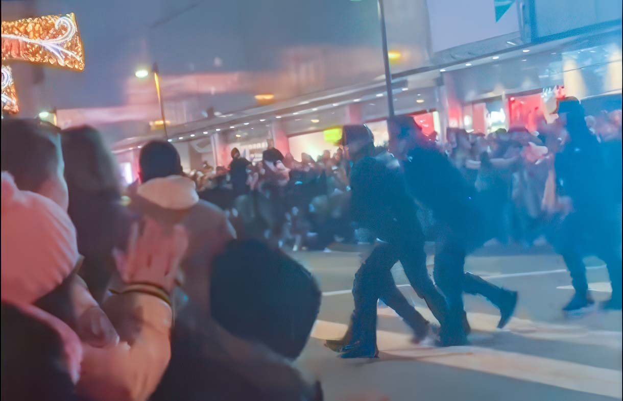 Dos Ertzainas retiran al individuo de la vía durante la Cabalgata de Reyes Magos de Vitoria-Gasteiz, un tercer agente les acompaña armado.