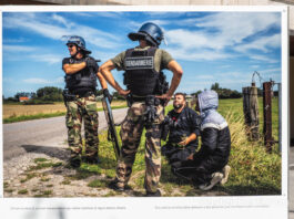 Fotografía de Sergi Cámara, parte de la exposición de "Éxodos" - Dos policías antidisturbios detienen a dos personas que intentaban subir a una barca.