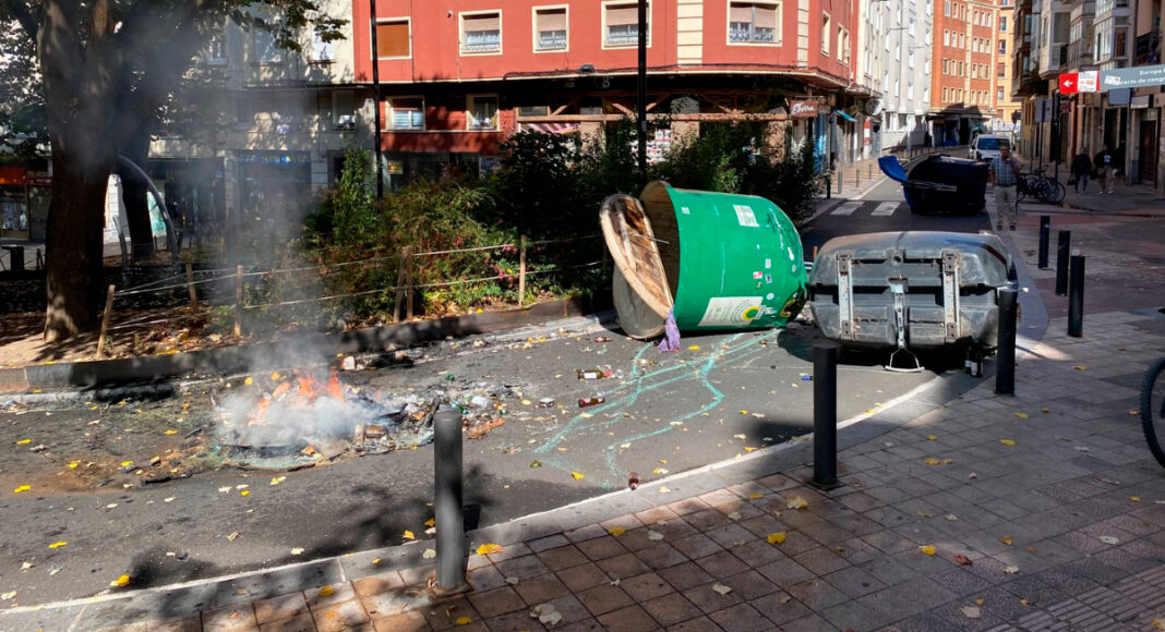 Contenedores volcados y restos de una barricada ardiendo tras los disturbios del 12 de octubre en Vitoria-Gasteiz.