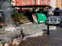 Contenedores volcados y restos de una barricada ardiendo tras los disturbios del 12 de octubre en Vitoria-Gasteiz.