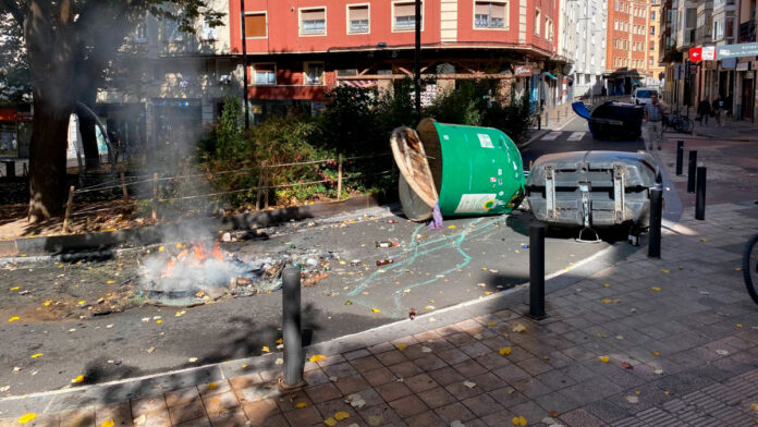 Contenedores volcados y restos de una barricada ardiendo tras los disturbios del 12 de octubre en Vitoria-Gasteiz.